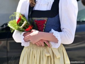 A member of a town band in Austria carries with flowers in her arms.